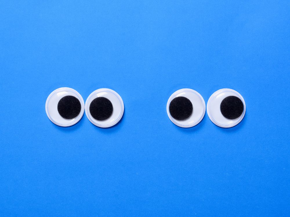 Dois pares de olhos móveis em fundo azul, ilustrando a complexidade dos músculos oculares e levantando a questão "o que causa estrabismo".