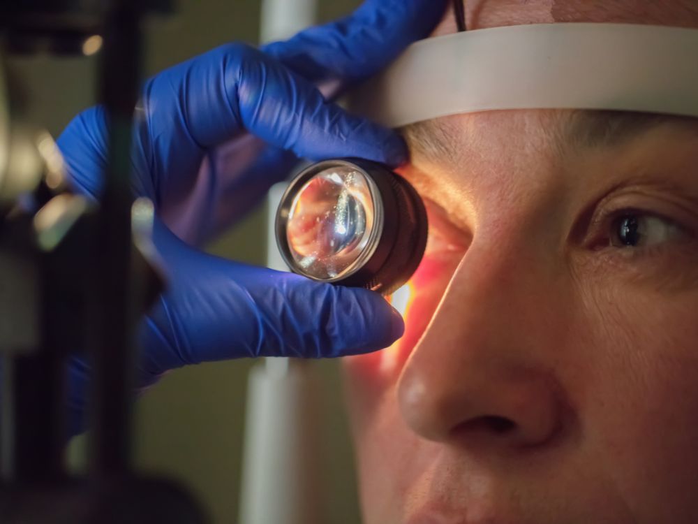 Oftalmologista utilizando lente de aumento para avaliar quanto tempo a visão fica embaçada após cirurgia de catarata.